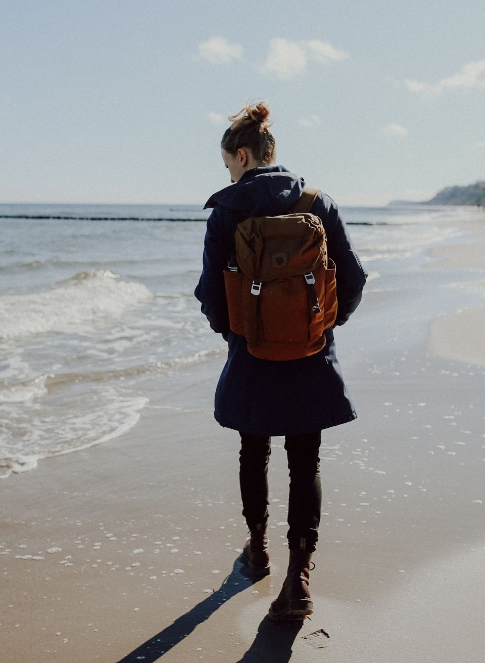 A walker wanders along the coast of the island of Usedom as the gentle waves lap the beach. Equipped with a rucksack, she sets off in search of hidden treasures such as amber, which can often be found on the shores here.