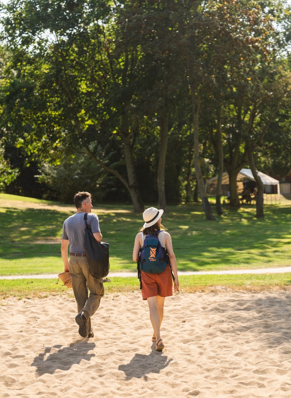 A couple walks through a green area towards the Stolper Fährkrug, with a sign in the foreground.