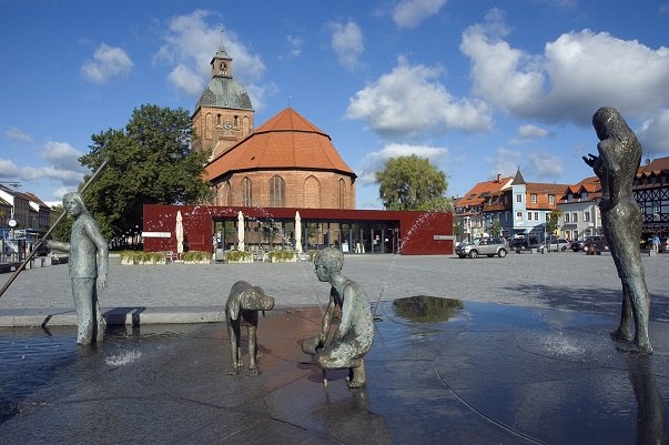 Marketplace Ribnitz with fountain "The Amber Fisherman" by Thomas Jastram, in the background Amber House with Tourist Information and St. Mary's Church, © Stadt RDG, Amt für Tourismus, Schule und Kultur