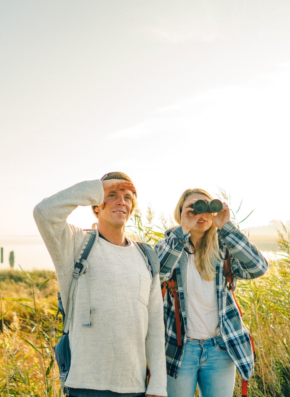 Two nature enthusiasts enjoy the peaceful landscape of the Vorpommersche Boddenlandschaft National Park while observing the diverse birdlife - a perfect moment to slow down amidst the impressive natural scenery.