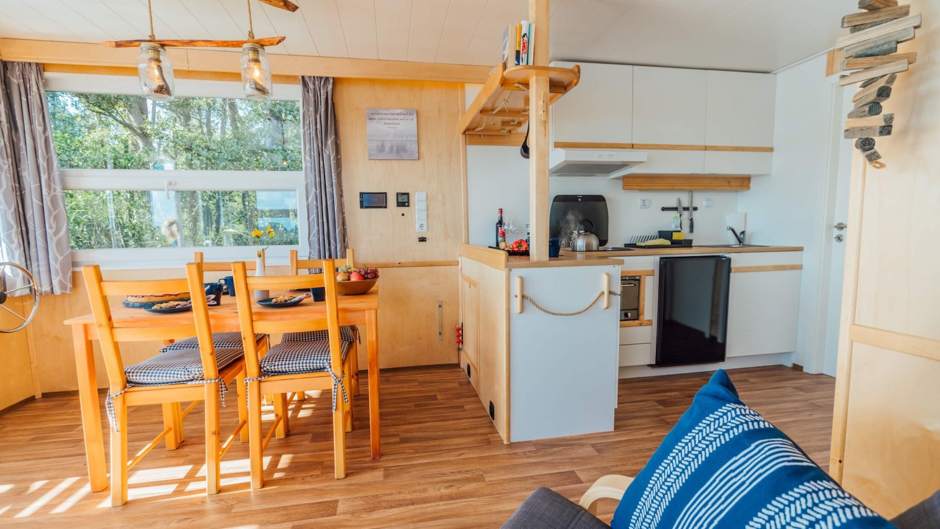 Interior of a houseboat on the Peene with dining area, kitchen and cozy furnishings.