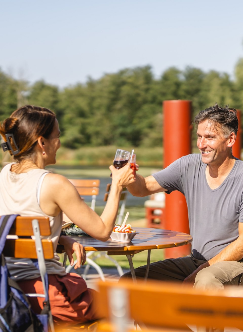 A couple enjoy a refreshment and a snack in the outdoor area of the Stolper Fährkrug with a view of the Peene.