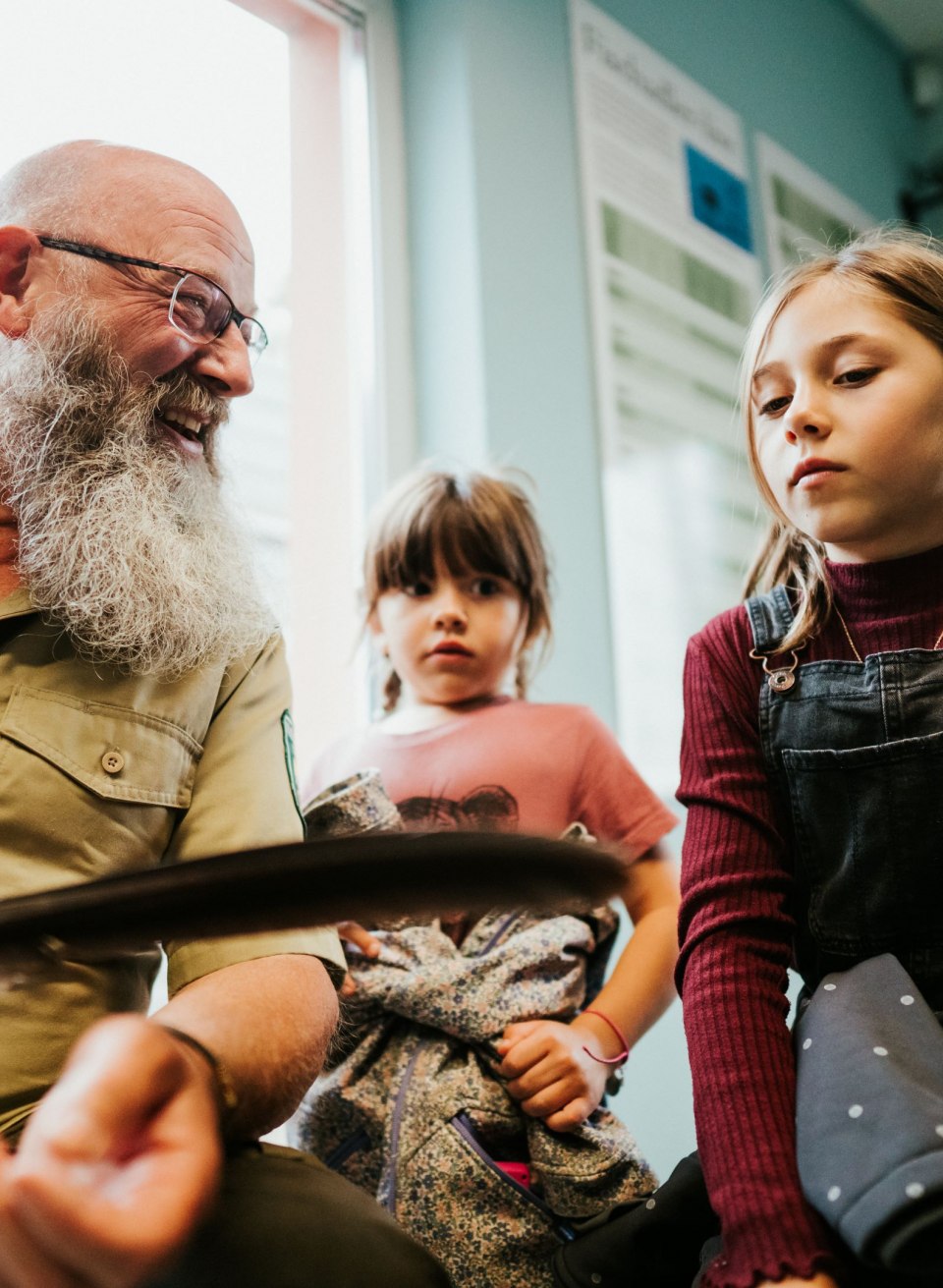 A ranger in the Müritz National Park explains exciting details about the local birdlife to two curious children during an eagle safari. With a feather in his hand, he brings them closer to the fascinating secrets of nature in a vivid way.