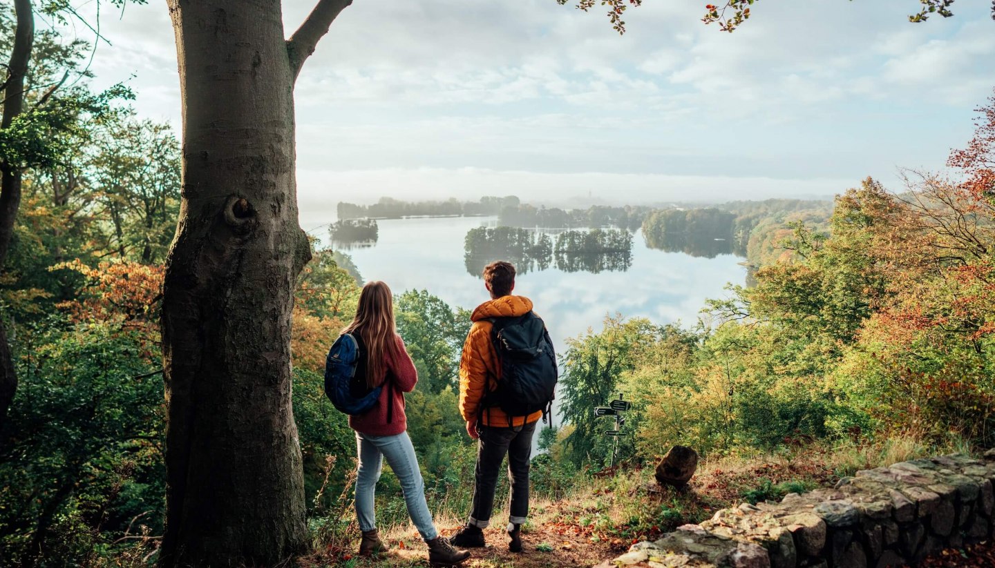 A couple looks down from the Reiherberg in Feldberg onto the Feldberger Haussee