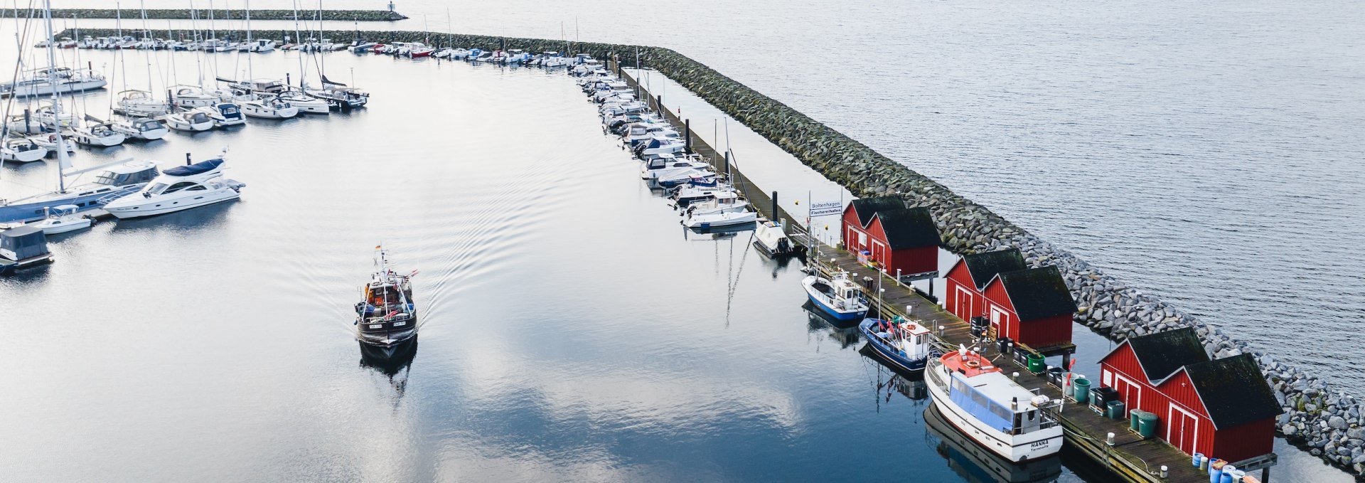 As you leave the fishing port of Boltenhagen, you pass the iconic red fishing sheds, which are beautifully reflected in the smooth water of the harbor basin., © TMV/Gross