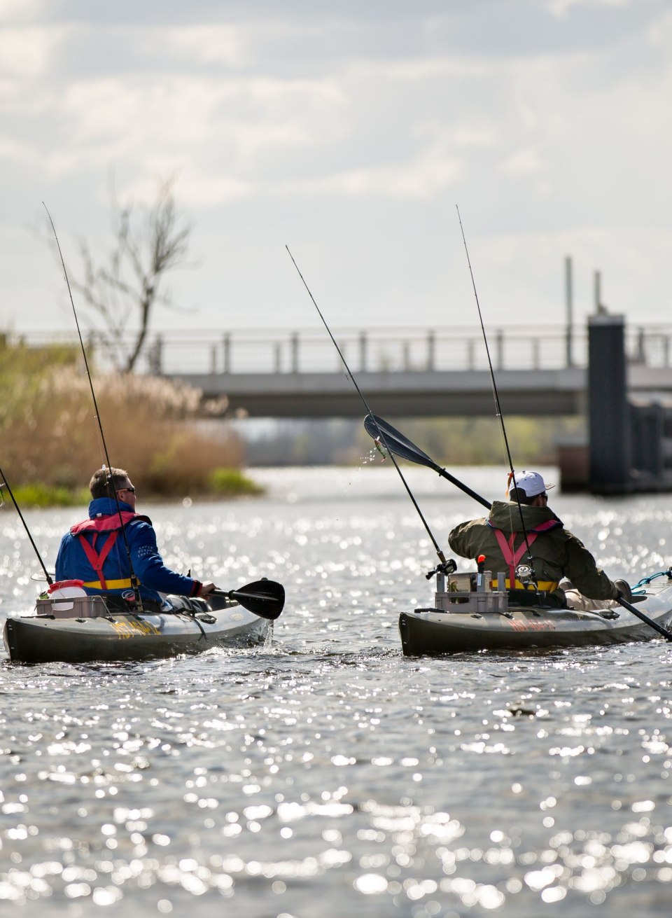 Two anglers paddle down the Peene in their kayaks while their rods are ready for the next catch. The peaceful atmosphere on the water and the glistening sunrays create the perfect backdrop for a relaxed fishing trip.