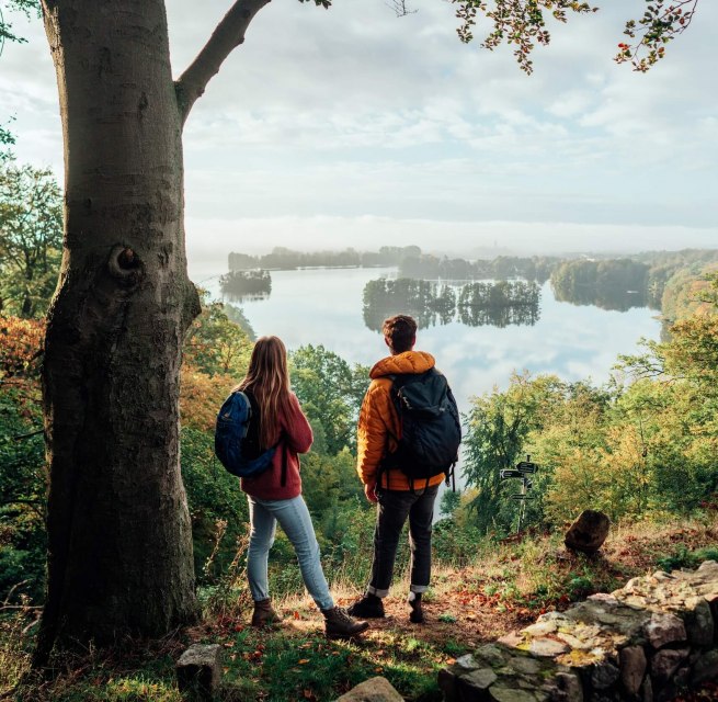 A couple looks down from the Reiherberg in Feldberg onto the Feldberger Haussee