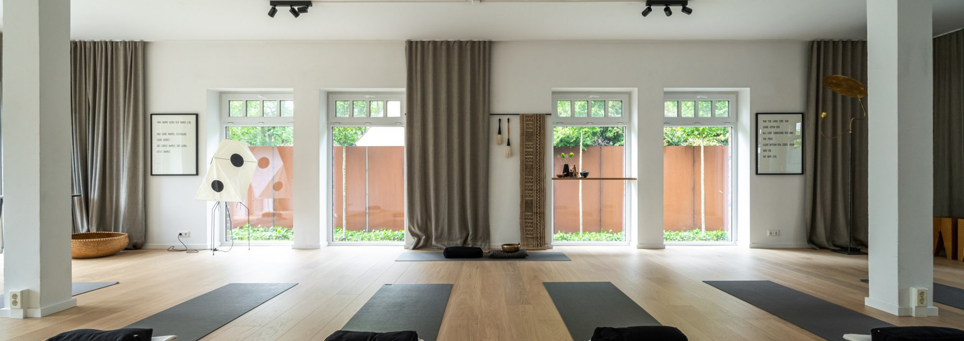 A modern, minimalist yoga and meditation room with light wooden floors, large windows and subtle decorations. The mats are already prepared for an upcoming yoga session, accompanied by soft cushions and towels., © Hotel Carpe Diem