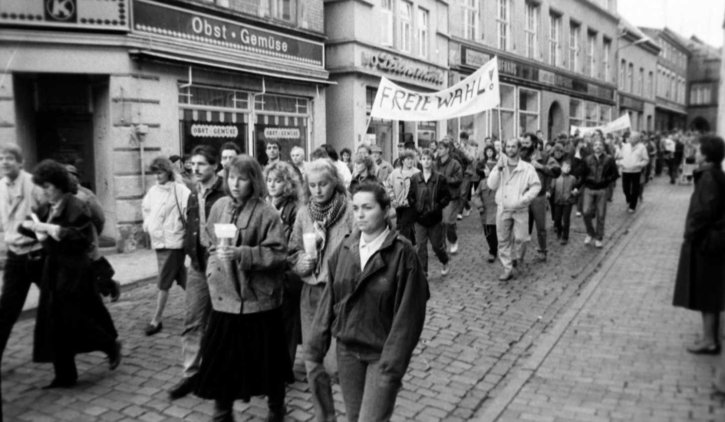 Demonstrators pass the former Parchimer Straße des Friedens, their banners calling for free elections., © Willy Voß