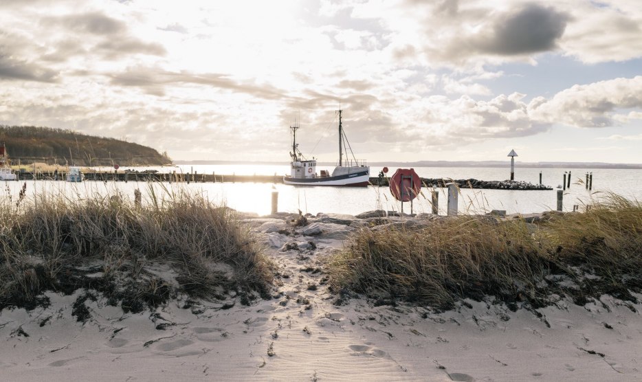 Walk on the beach with a view of a fishing cutter lying in the Baltic Sea in the harbor of Timmendorf on the island of Poel., © VMO, Alexander Rudolph