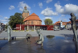 Marketplace Ribnitz with fountain "The Amber Fisherman" by Thomas Jastram, in the background Amber House with Tourist Information and St. Mary's Church, © Stadt RDG, Amt für Tourismus, Schule und Kultur