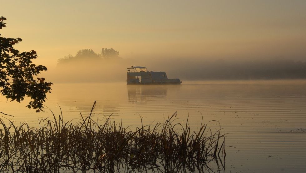 Sunrise on the lake: in the middle of it a floating caravan, © freecamper