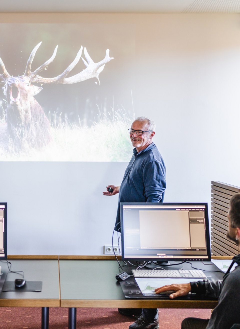 A lecturer presents a photo of a stag to workshop participants in the Max Hünten Haus.